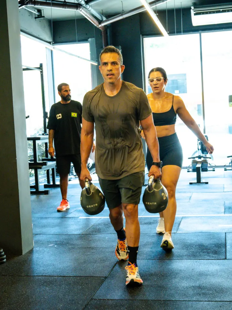 Dupla no farmers carry com kettlebells